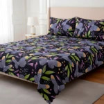 Tendido de cama doble faz diseño de mariposas y hojas sobre fondo negro.