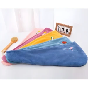 Toallas de microfibra para cabello, apiladas en varios colores pastel: azul, celeste, amarillo, rosa y morado. Incluyen diseños de frutas y luna.