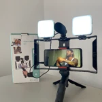 Trípode portátil con soporte para celular, micrófono y dos luces LED cuadradas, ideal para video y audio.