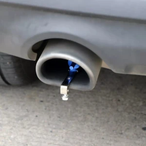 Silbato de sonido turbo azul metálico instalado en tubo de escape de automóvil, simula rugido deportivo.