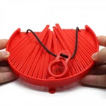 Colador Better Strainer rojo con soporte de plástico y cordón negro, sujetado por manos.