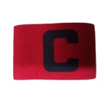 Brazalete de capitán de fútbol rojo con letra C negra, material elástico, usado en el brazo.