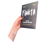 Paquete negro de parches cicatrizantes Finkta con letras blancas. Una mano lo sostiene en ángulo diagonal, mostrando un tatuaje de mano en el antebrazo de la persona.