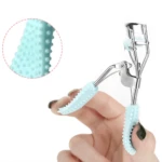 Encrespador de pestañas manual azul con textura de puntos y pomo de maquillaje en mano.