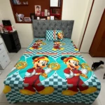 Sábana infantil con estampado de Mickey Mouse en tonos turquesa y rojo, sobre cama con cabecero gris tapizado.