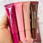Cuatro tubos de Peptide Lip Tint R1642 en tonos fucsia, rosa, durazno y marrón, sostenidos en una mano, listos para usar.
