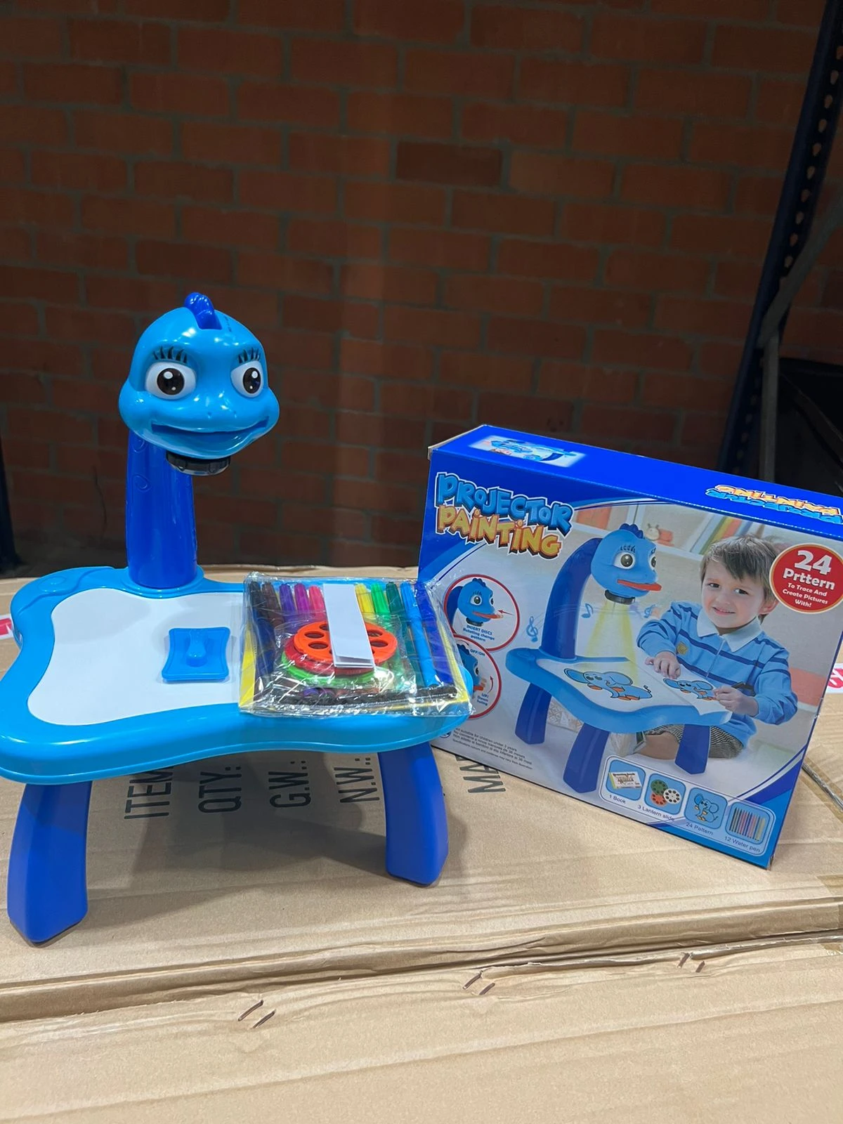 Escritorio de aprendizaje interactivo azul con personaje animado, incluye pizarra, lápices de colores y caja de regalo.