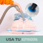 Bolsas al vacío comprimiendo ropa de cama rosada y un edredón con estampado floral, usando aspiradora.