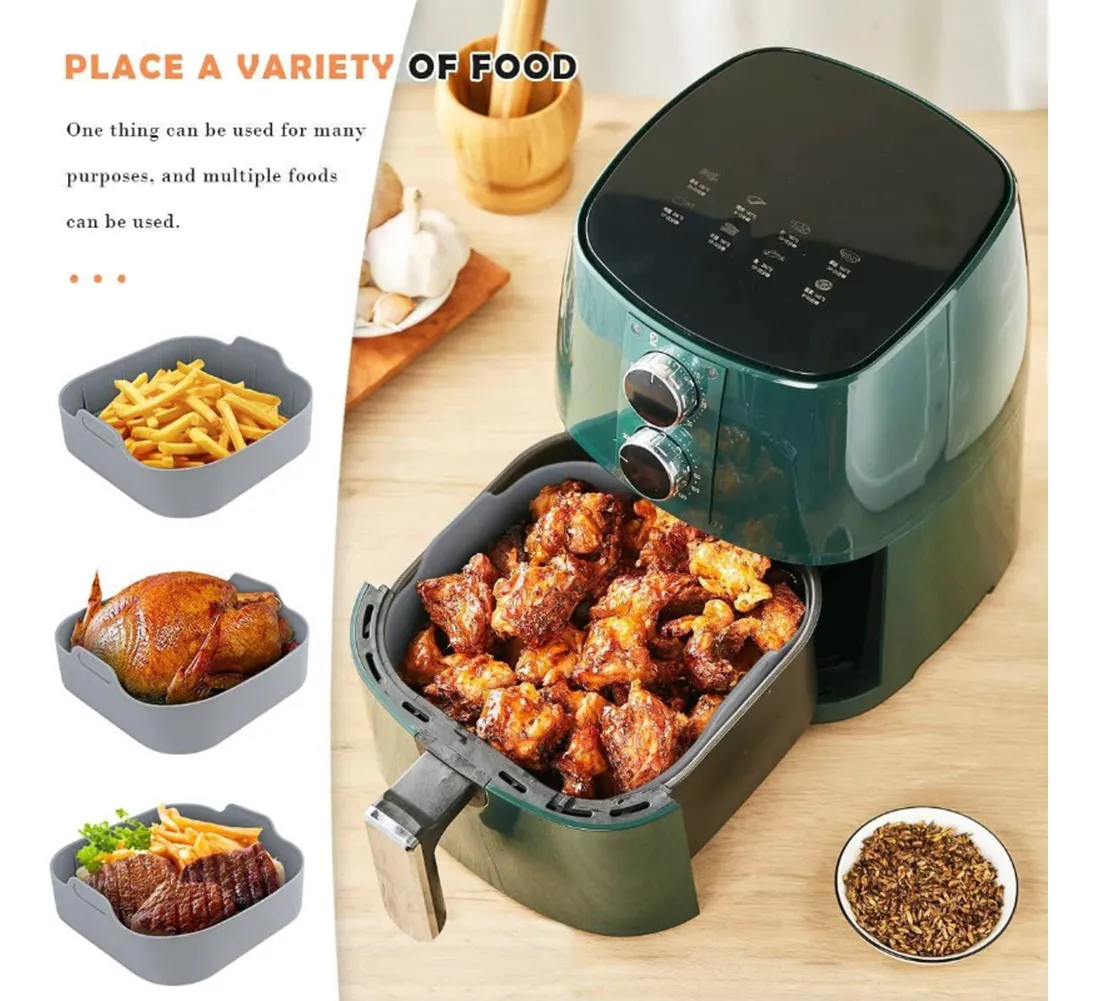 Freidora de aire verde con bandeja de silicona gris para cocinar pollo y patatas fritas, mostrando alimentos dorados y crujientes en su interior.