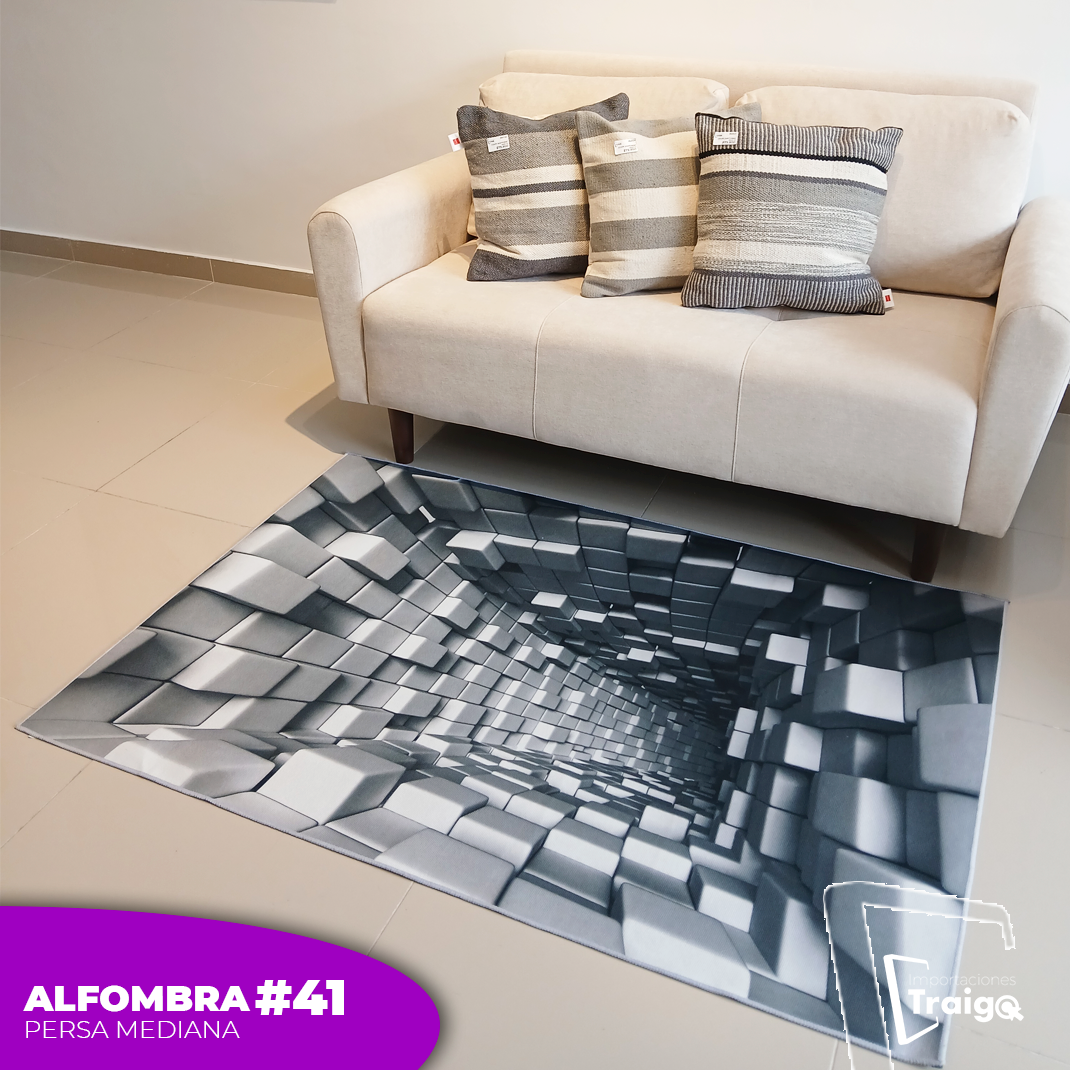 Alfombra rectangular gris con efecto tridimensional de bloques, colocada frente a sofá beige en sala.