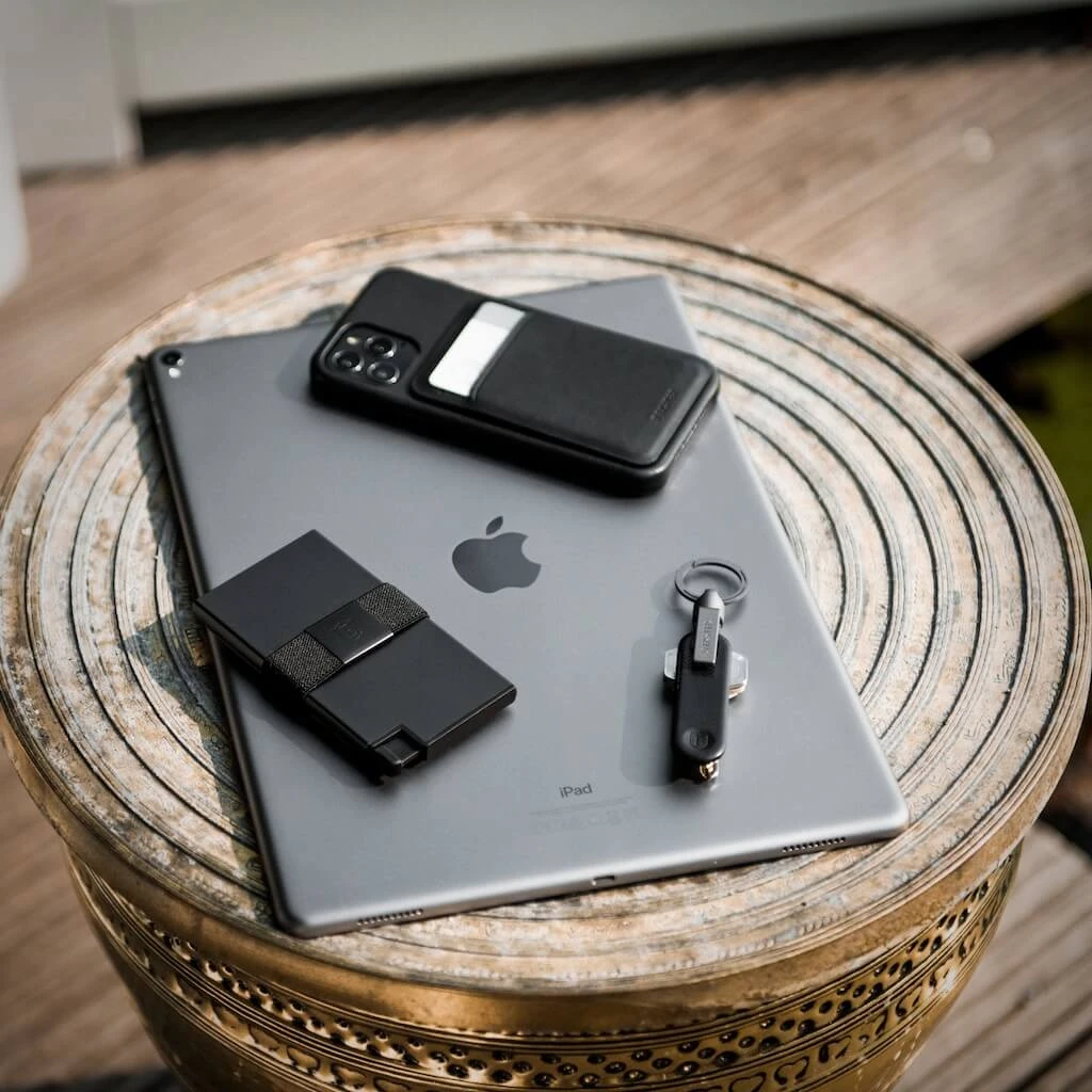 Set de dos tarjeteros Flikt Premium en negro, con protección RFID, sobre una tablet Apple en mesa de madera.
