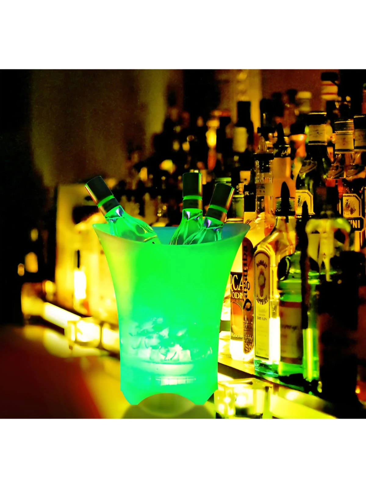 Cubeta de hielera LED verde brillante con botellas de alcohol dentro, sobre barra de bar con estantería de licores al fondo.