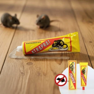 Tubo de pegante para ratas Atrapra, amarillo con rojo, y dos cajas pequeñas con el mismo pegante, sobre madera.