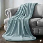 Cobija de piel de conejo color turquesa sobre sofá gris. Textura lisa y suave cayendo en pliegues naturales por el respaldo y asiento del mueble.