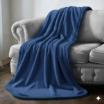 Cobija de piel de conejo color azul sobre sofá gris claro. Textura suave y lisa, drapeada mostrando su caída natural en un ambiente de sala de estar.