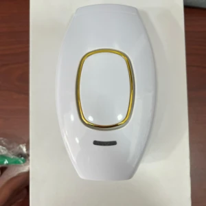 Depiladora láser IPL blanca con borde dorado, para cuerpo y rostro, sobre caja blanca.