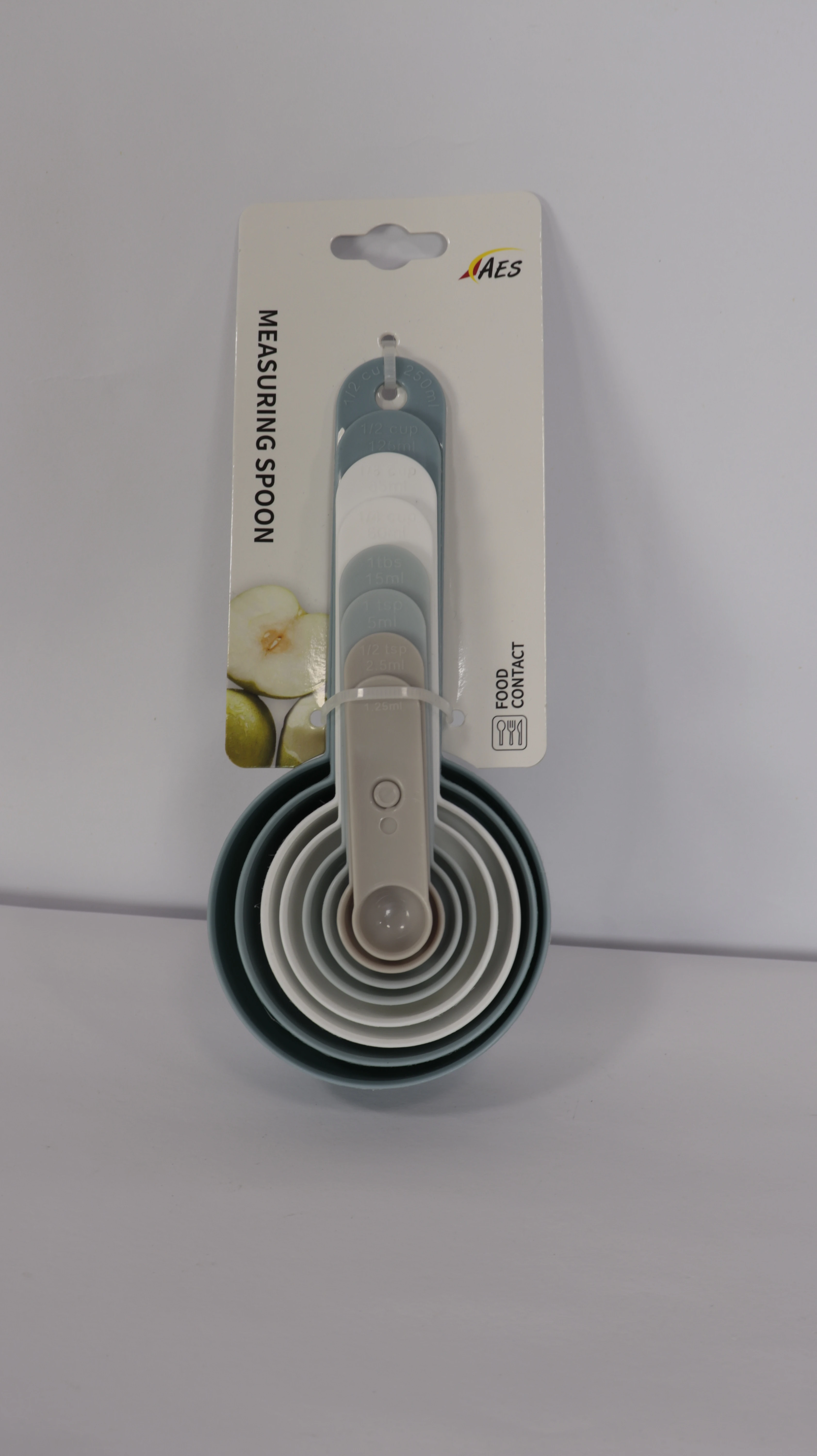 Set de cuatro cucharas medidoras de cocina en empaque, con mango de silicona gris y anillos concéntricos en tonos claros y oscuros, diseñadas para medir ingredientes con precisión.