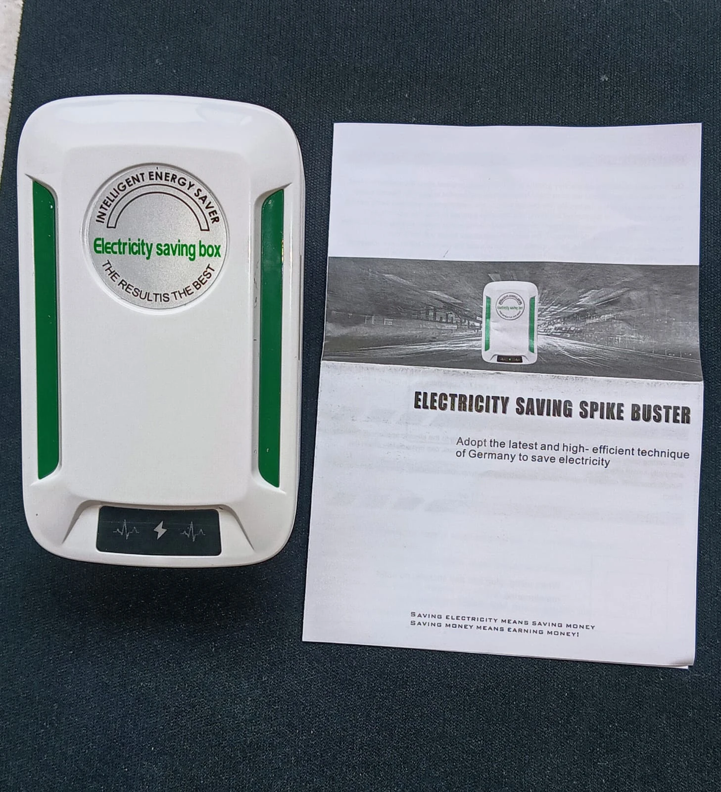Regulador de voltaje inteligente blanco con detalles verdes, acompañado de su manual. Incluye caja compacta con indicadores LED y texto en español sobre ahorro energético.
