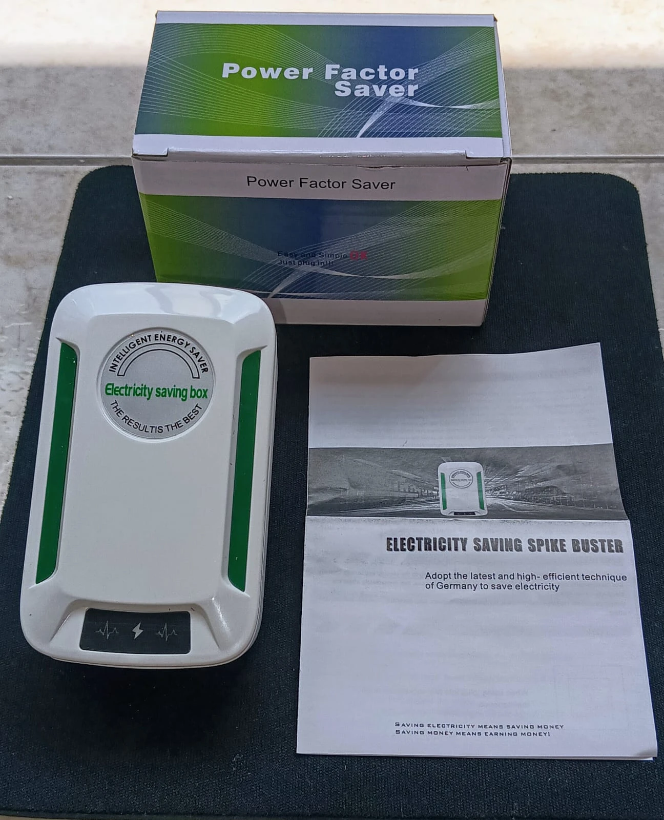 Set de dos reguladores de voltaje inteligentes en caja y dispositivo blanco con detalles verdes, junto a su manual. Incluye caja de cartón con diseño verde y blanco, dispositivo compacto con pantalla LED y manual impreso.