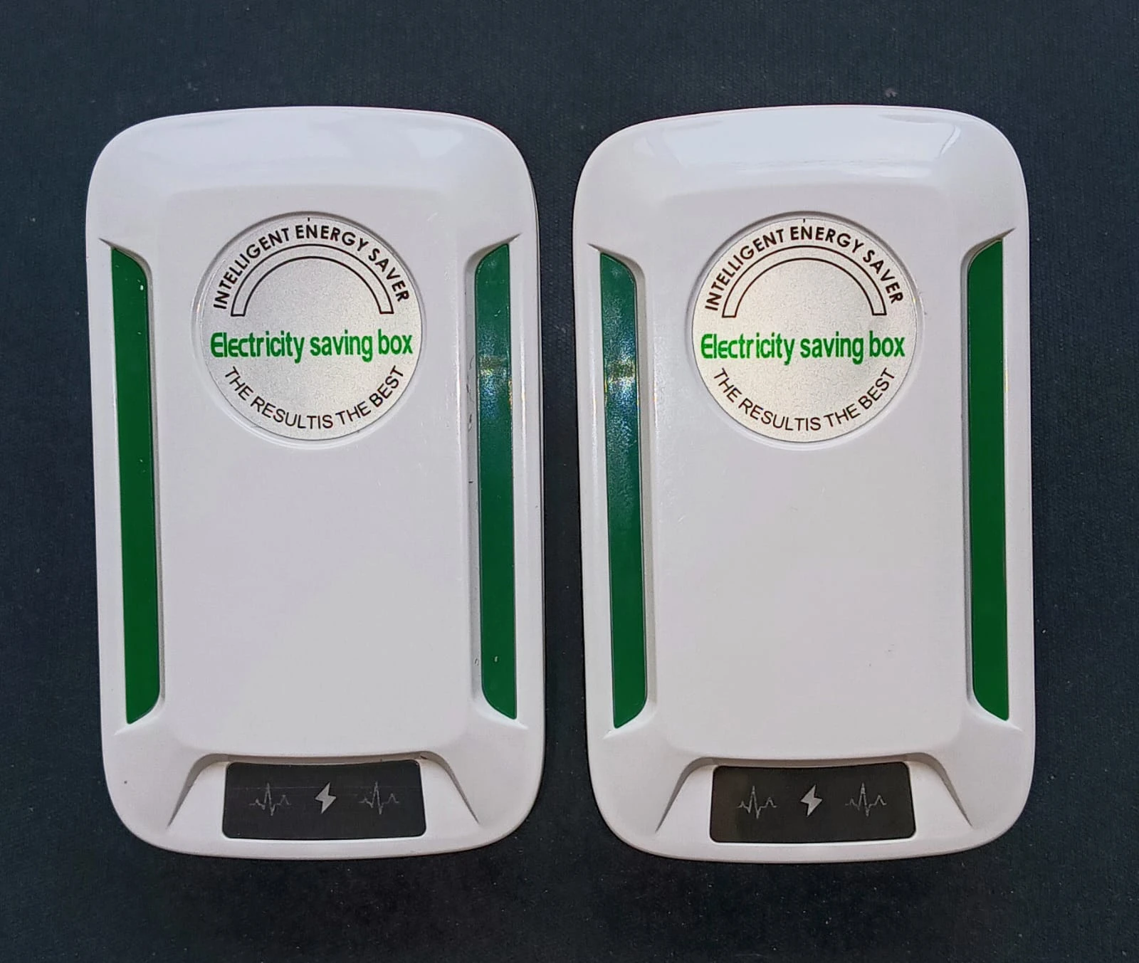 Dos reguladores de voltaje inteligentes en color blanco con detalles en verde, mostrando la etiqueta frontal con texto descriptivo y símbolos de protección eléctrica.