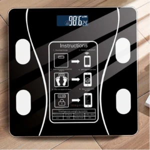Pesa digital de baño negra con pantalla LED mostrando 98.6 y 24°C, instrucciones de uso y tabla de especificaciones.