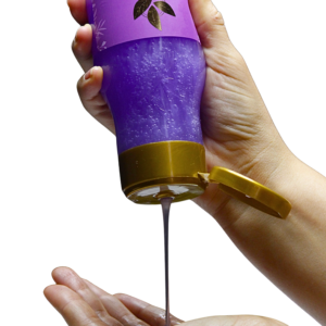 Bote de champú de cebolla con tapa dorada, contenido violeta brillante, siendo vertido en la mano sobre fondo negro.