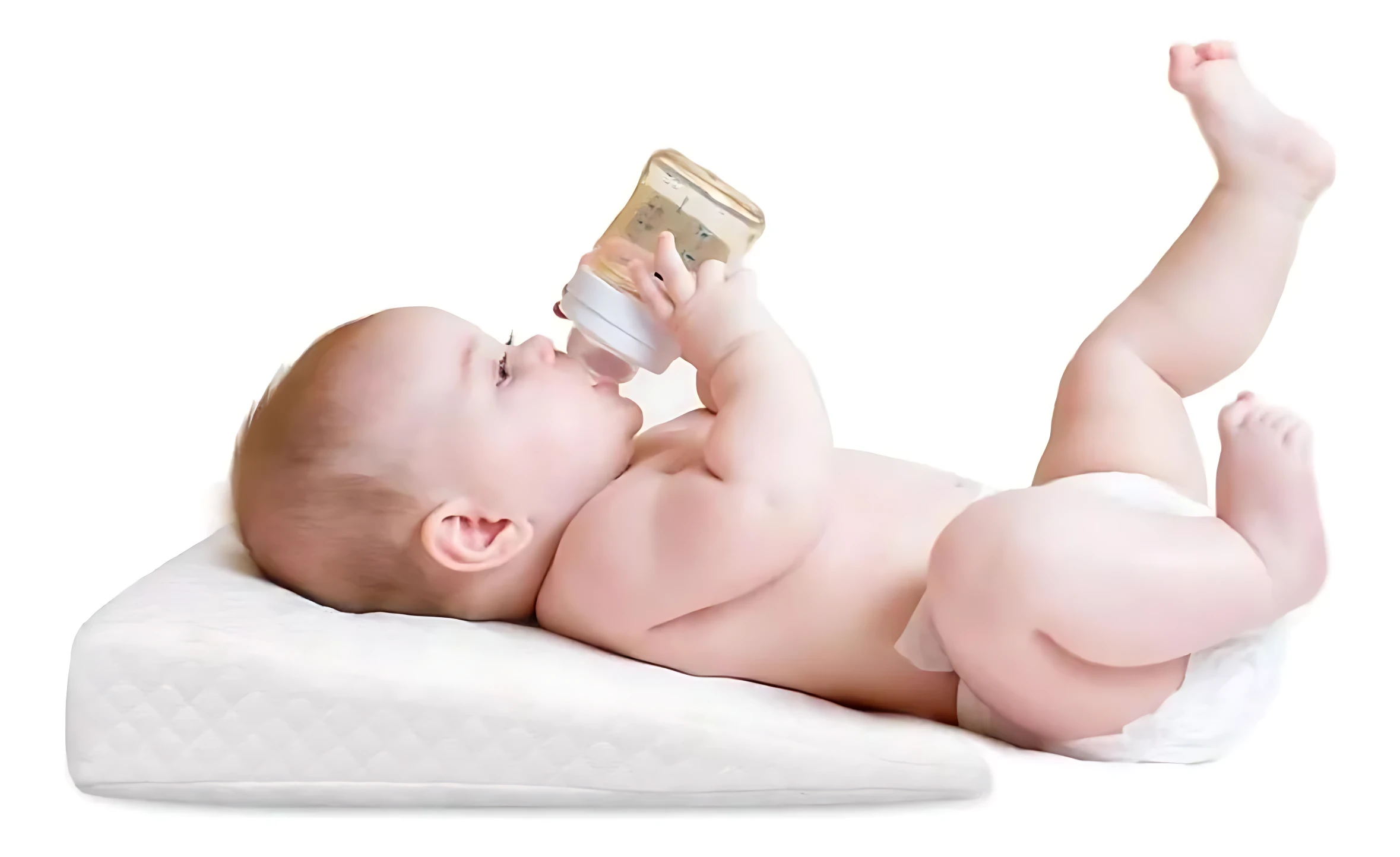 Bebé en pañal tomando tetero sobre almohada antireflujo blanca para colecho, previene regurgitación.