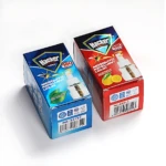 Dos cajas de líquido repelente de mosquitos Hacker, una azul con aroma a limón y otra roja con aroma a naranja, mostrando el frasco transparente y etiquetas con códigos de barras.