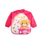 Babero delantal manga larga rosa con estampado de osito conduciendo un coche y notas musicales.