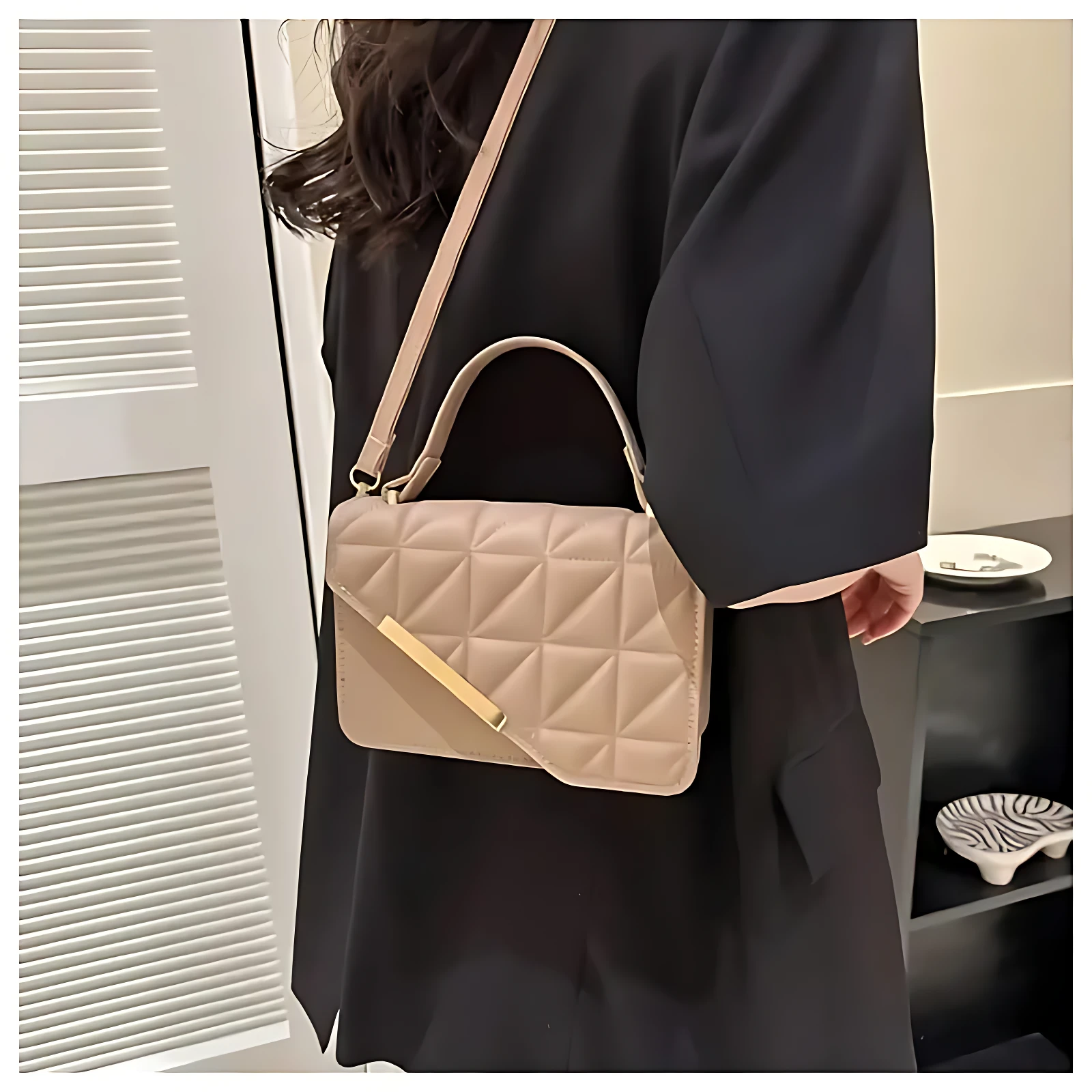 Bolso cartera beige acolchado con tapa diagonal y detalle dorado, colgado al hombro.