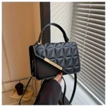 Bolso cartera negra acolchada con tapa diagonal y herraje dorado, ideal para uso diario.