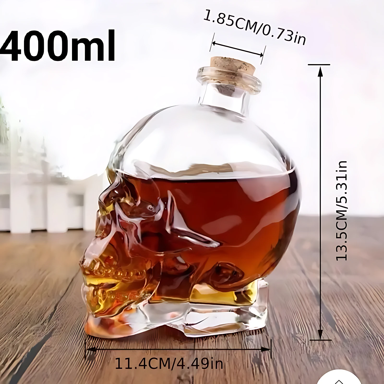 Botella de vidrio con forma de calavera, capacidad de 400 ml, mide 13.5 cm de alto y 11.4 cm de ancho, contiene líquido marrón, ideal para servir bebidas en fiestas.