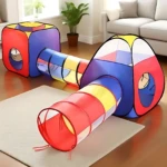 Carpa modular para niños con túnel de colores rojo, azul y amarillo, montada sobre alfombra en sala de estar.
