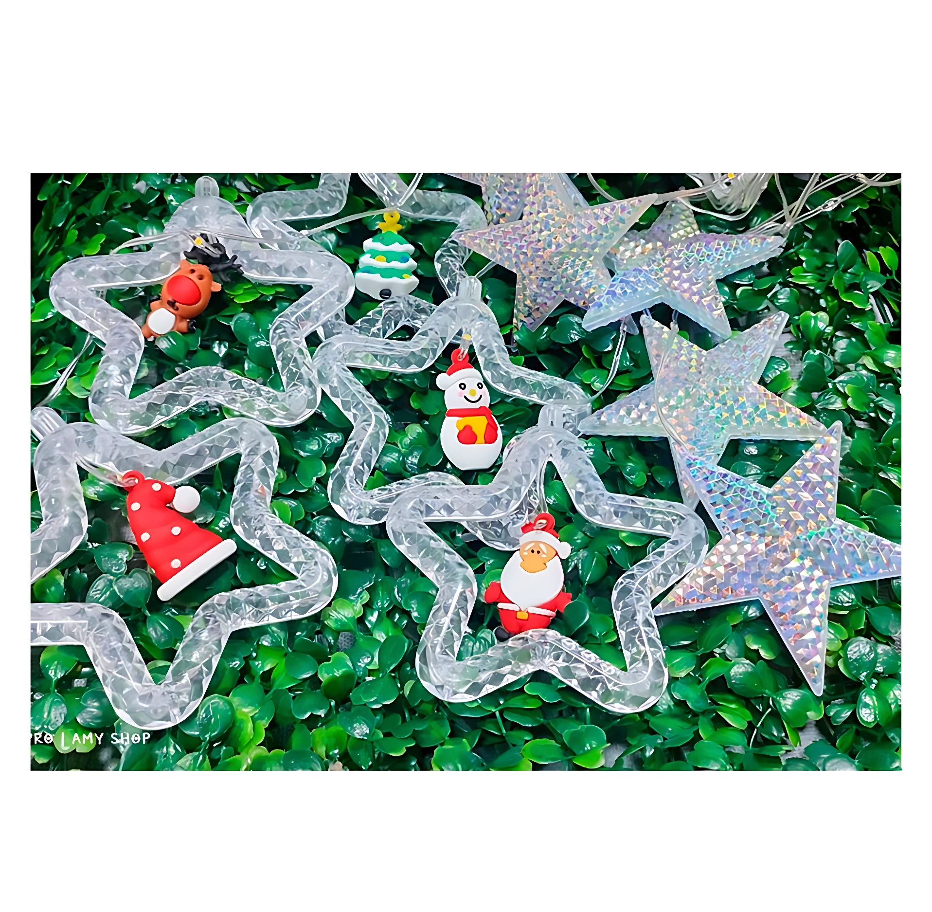 Cortina de luces LED en forma de estrellas con efecto tornasol y figuras navideñas colgantes como Santa, renos y muñeco de nieve sobre fondo verde.