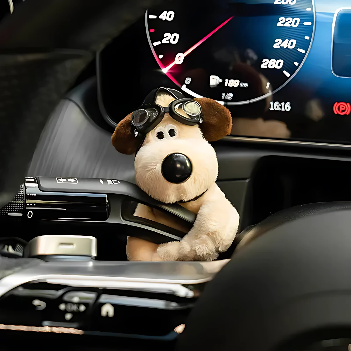 Peluche perro con gafas de piloto, color beige y marrón, colocado en el tablero de un vehículo.