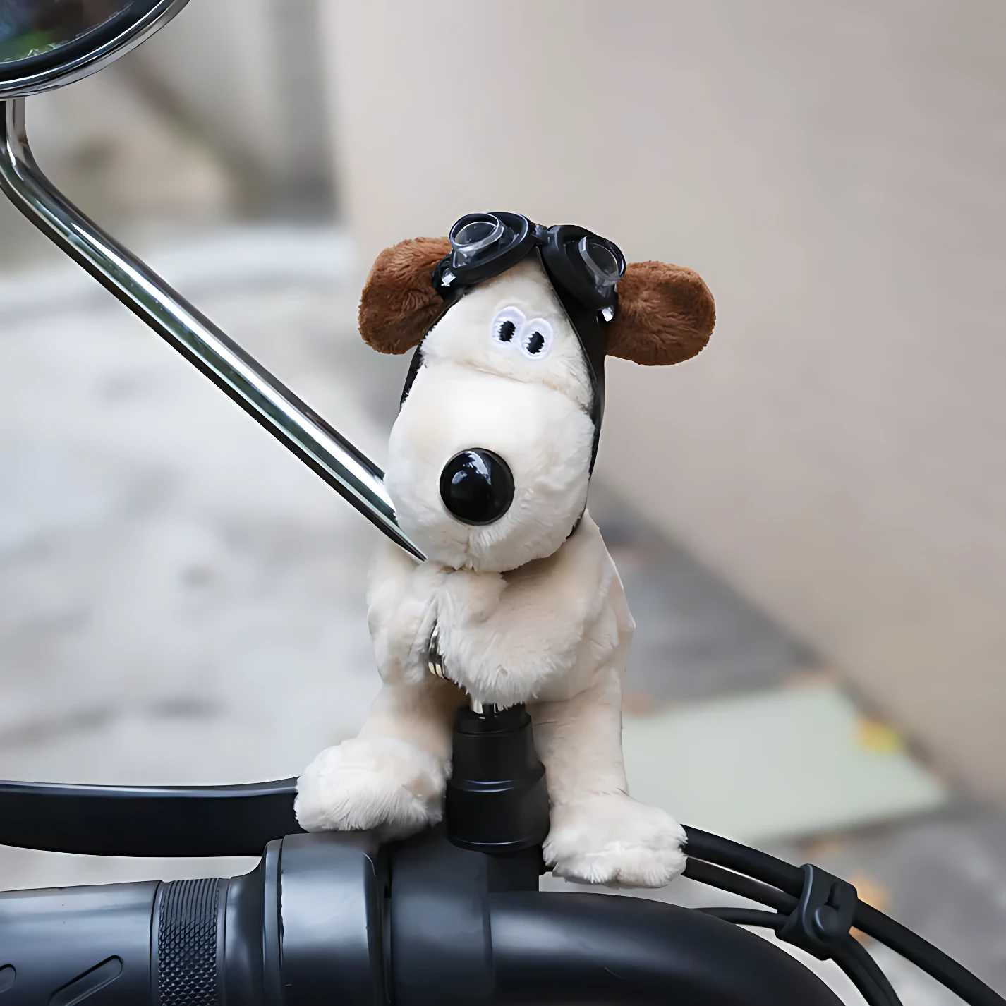 Peluche perro blanco con gafas de piloto, sentado en el manillar de una motocicleta.