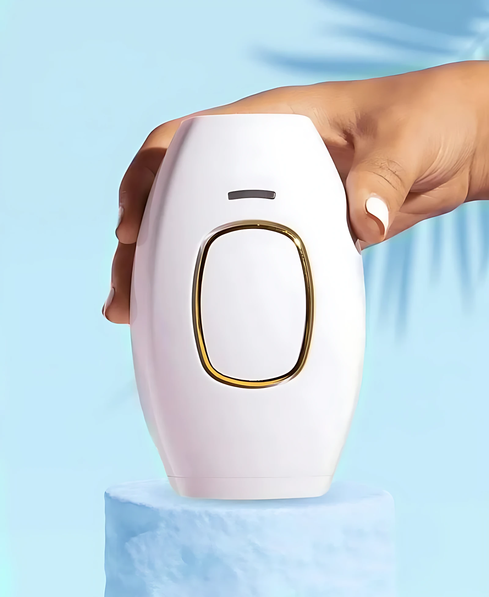Depiladora láser IPL blanca con borde dorado, sostenida por mano con uñas blancas, sobre pedestal azul.