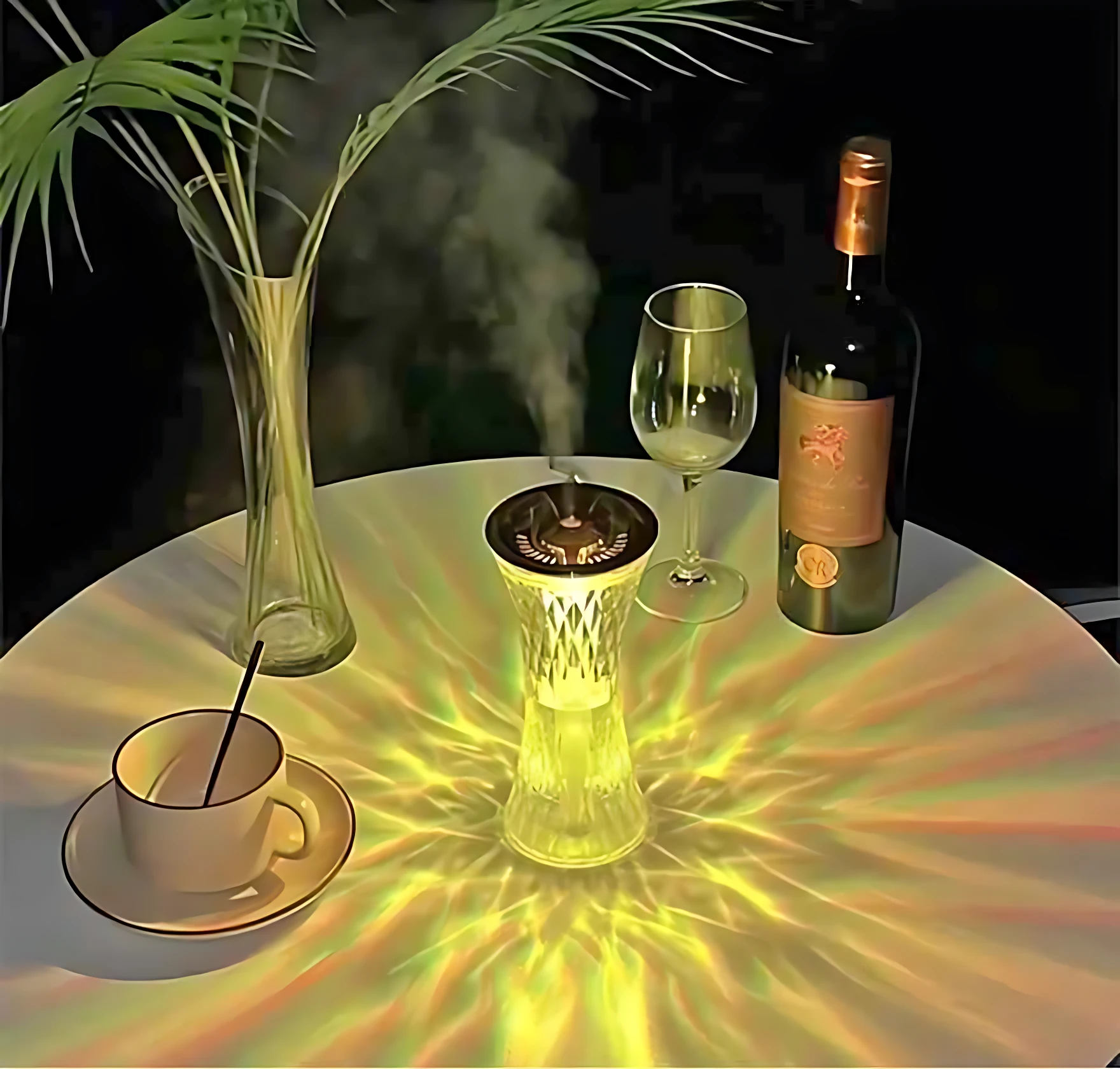 Difusor ultrasónico LED en jarra de cristal transparente, emitiendo luz cálida con proyección radial sobre mesa redonda. Acompañado de copa de vino, botella y taza con palillo, junto a flor en jarrón alto. Ambiente relajante y decorativo.