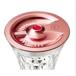 Difusor ultrasónico aroma en jarra de cristal tallado con tapa metálica rosa, luz LED roja visible y botón de encendido.