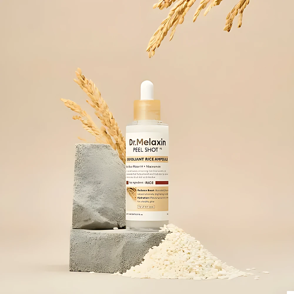 Ampolla facial Dr.Melaxin Peel Shot con arroz blanco y niacinamida, sobre pedestal de concreto, rodeada de arroz y espigas.