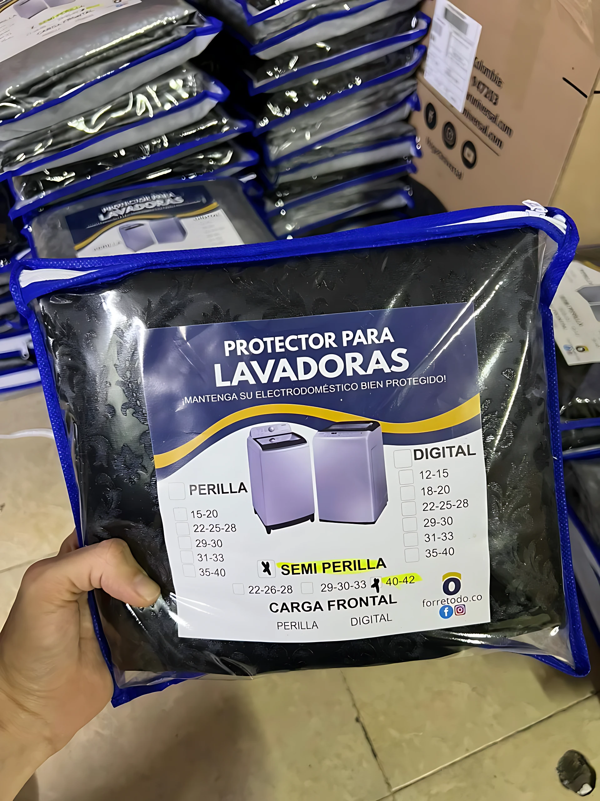 Protector impermeable negro para lavadora de carga frontal en bolsa plástica con costura azul. La etiqueta muestra compatibilidad con modelos de perilla, digital y semi perilla.