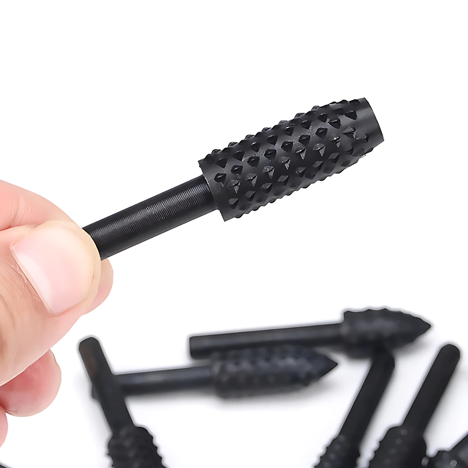 Fresa rotativa negra para madera con cabeza texturizada de púas, sostenida por una mano. Varias piezas del set desenfocadas al fondo sobre fondo blanco.