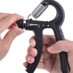 Ejercitador de mano negro con resistencia ajustable de 5 a 60 kg, manos ajustando la perilla.