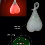 Luz LED roja en forma de corazón para bicicleta, colgando del asiento, con detalle de circuito y switch.