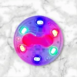 Luces traseras para bicicleta recargables USB, modelo circular con seis LEDs multicolores en tonos neón sobre base translúcida, vista superior sobre superficie de mármol blanco.
