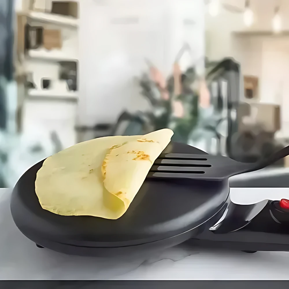 Máquina eléctrica crepes Sokany compacta en uso, con crepe dorado sobre placa negra y mango ergonómico.