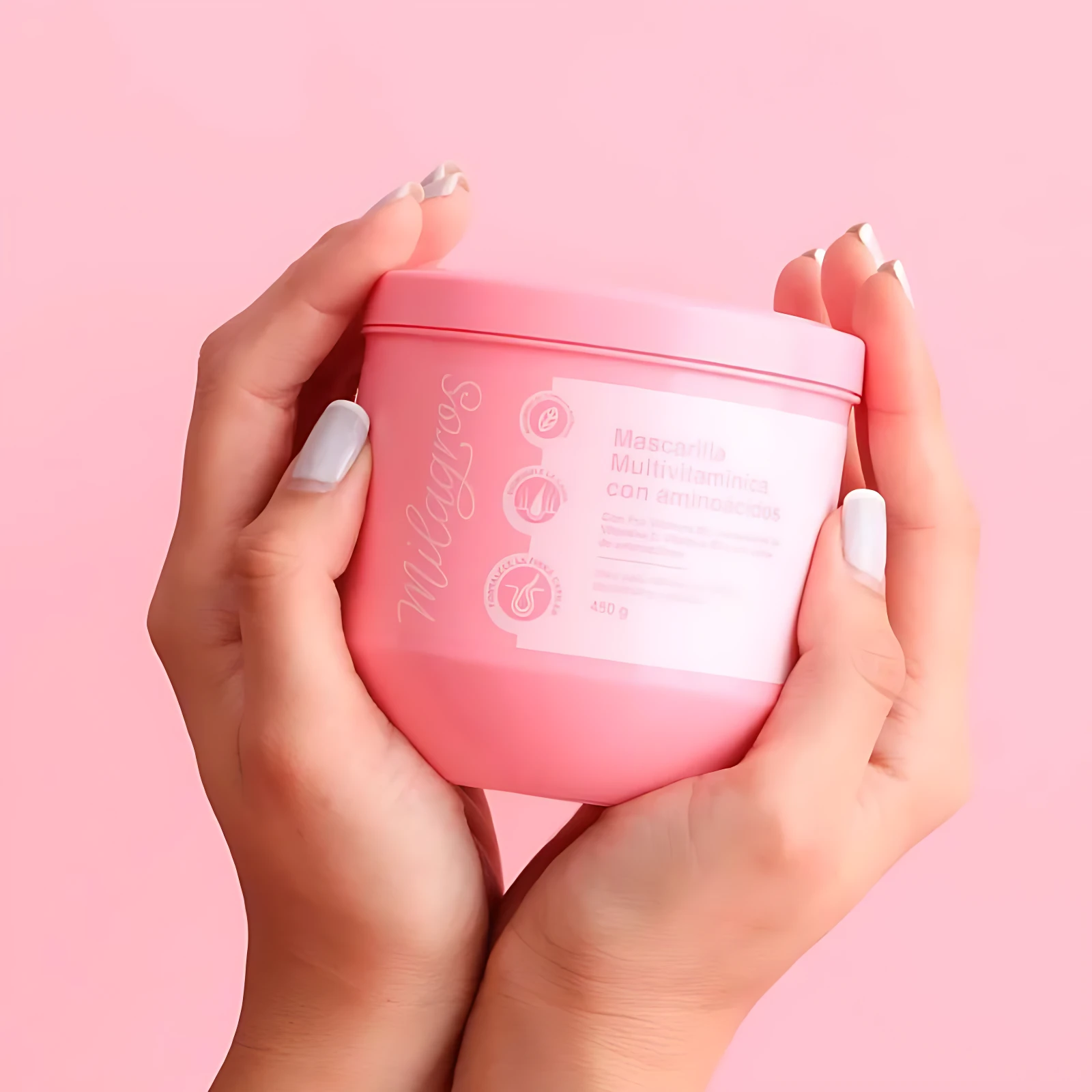 Manos sostienen tarro rosa de Mascarilla Milagros Multivitamínica con Aminoácidos, 450g.