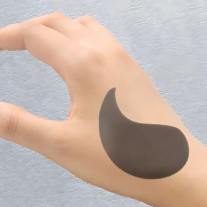 Parche negro revitalizante para ojeras y bolsas, posado sobre mano.
