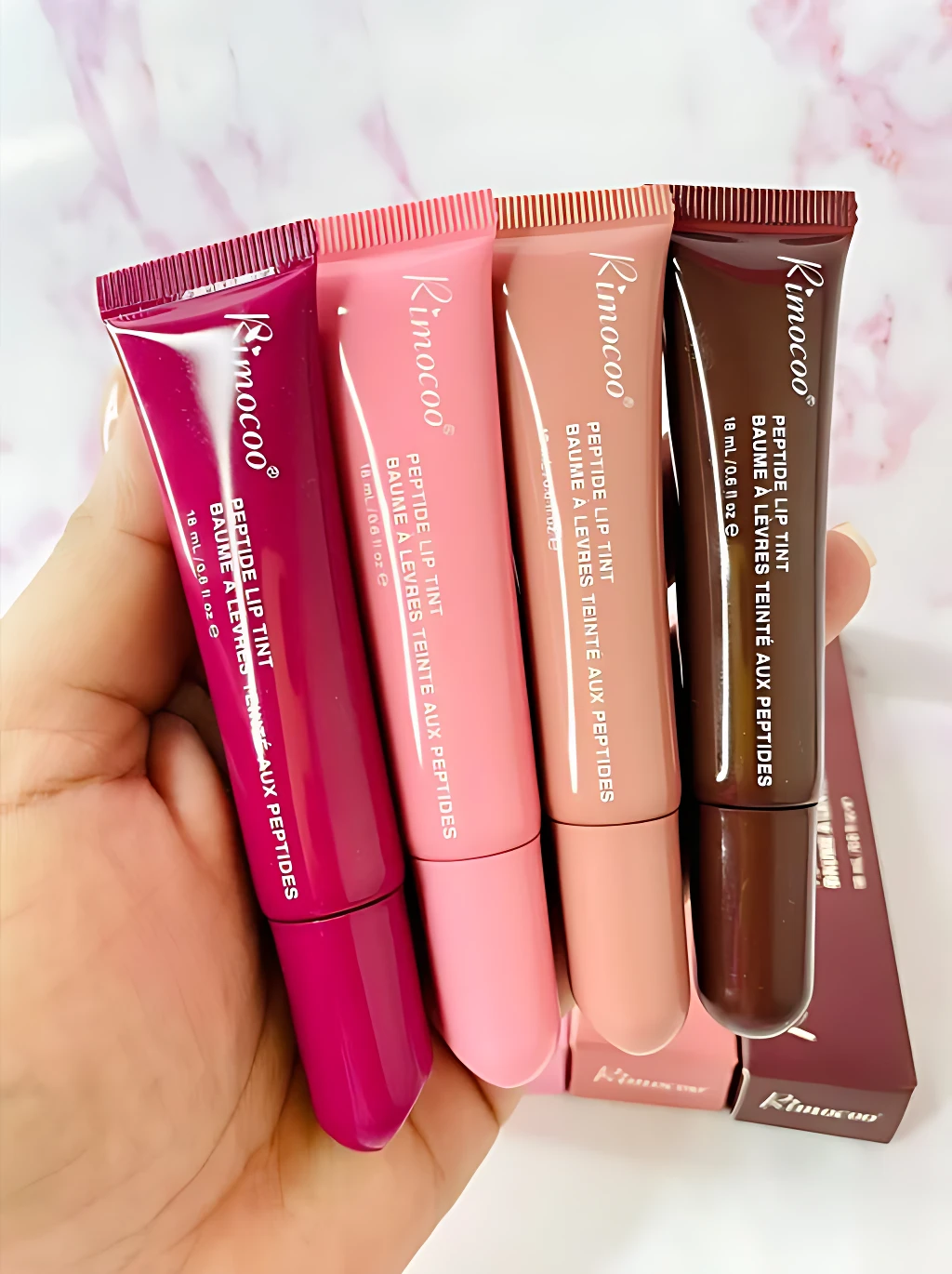 Set x4 bálsamos labiales Rimocoo, tonos rosa, melocotón y marrón, con péptidos para hidratación y color natural.