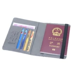 Protector pasaporte abierto en color gris, mostrando interior con ranuras para tarjetas y espacio para documentos. Incluye pasaporte chino visible y banda elástica negra.
